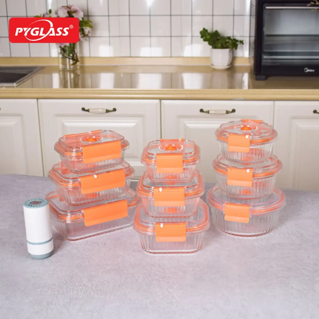 Set of transparent food storage containers with orange lids displayed on a kitchen counter, next to a white kitchen roll.